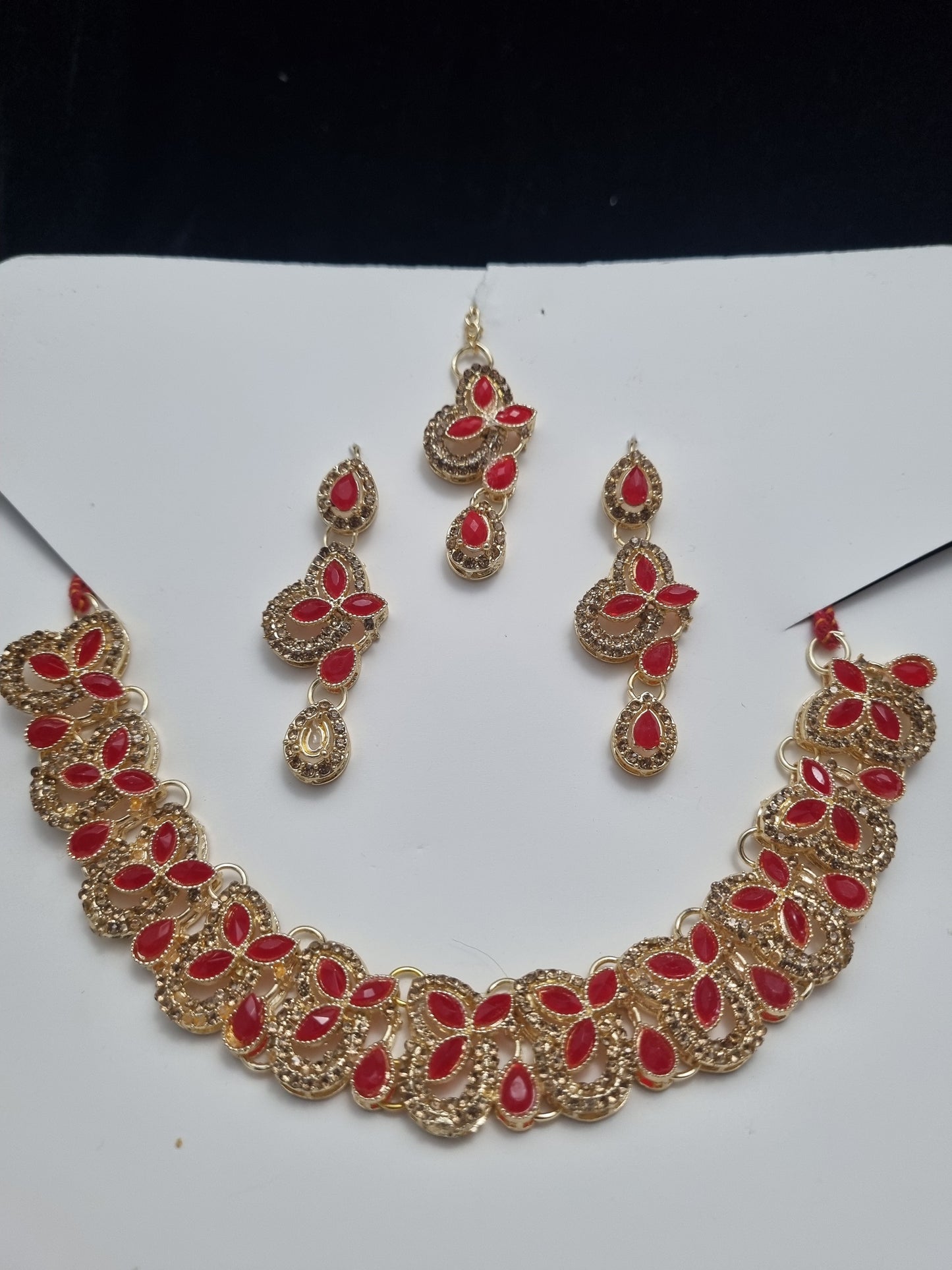 Elegant golden necklace set adorned with vibrant red stones and intricate craftsmanship.