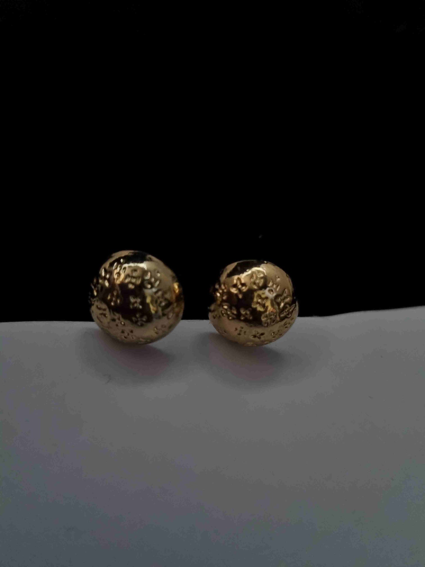 Golden textured ball earrings with intricate detailing.