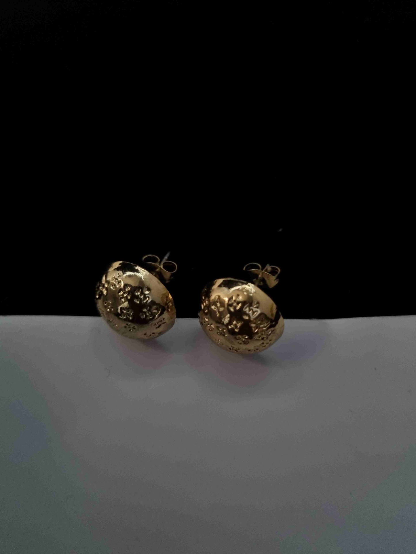 Golden textured ball earrings with intricate detailing.