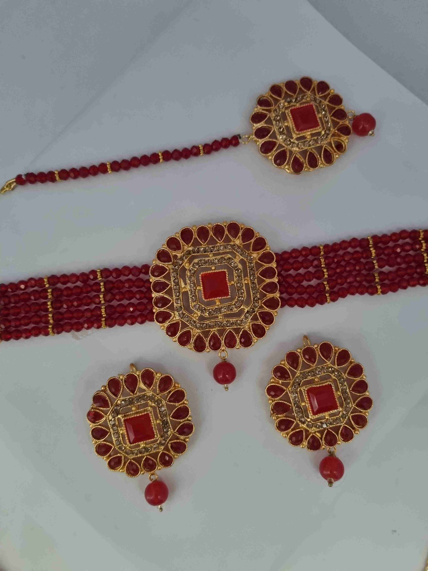 Gold and red antique bridal jewelry set with earrings, a choker necklace, and a matching tikka.