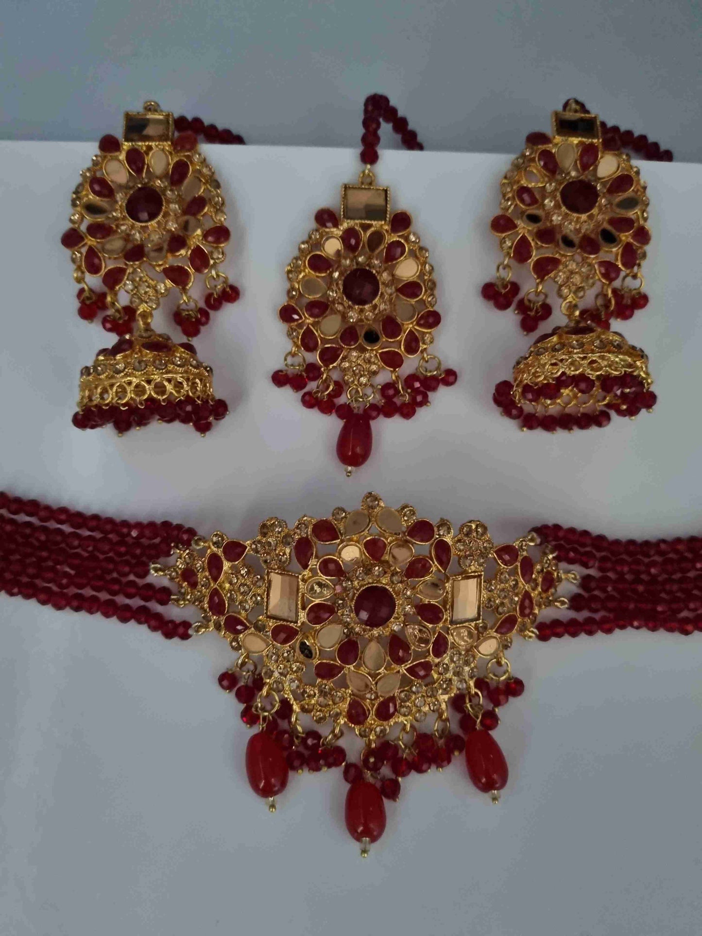 Gold and red Kundan bridal jewelry set with earrings, Jhumkas, and a choker necklace.
